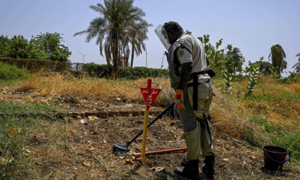 A deminer uses a metal probe as he searches for land mines in Al-Mugran Park in Khartoum on April 19, 2026. AFP