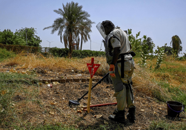 A deminer uses a metal probe as he searches for land mines in Al-Mugran Park in Khartoum on April 19, 2026. AFP